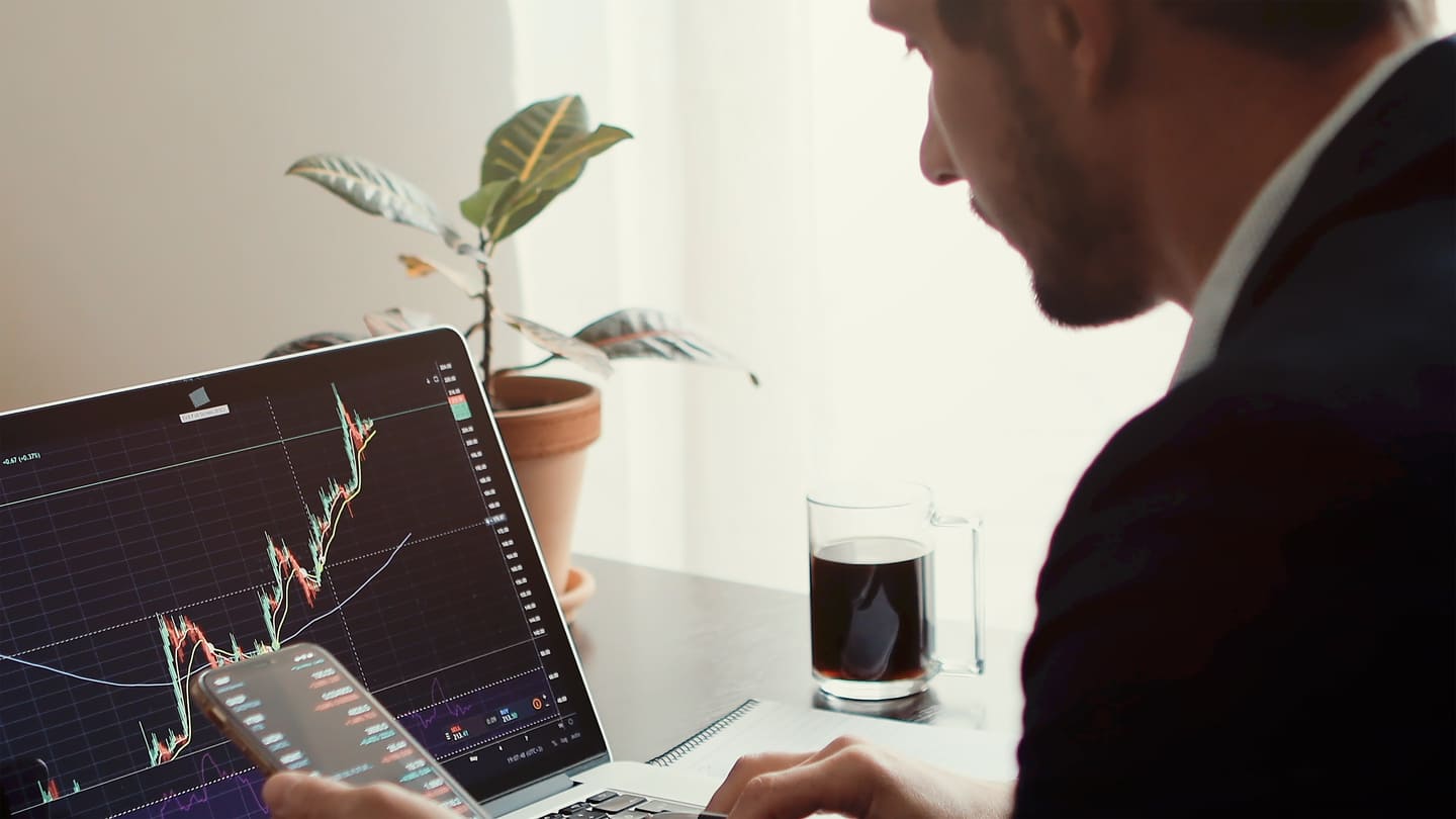 A man in front of his computador and his telefone analyzing charts to determine the best transfer pricing method for his Brazilian company.